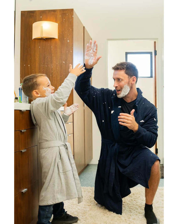 Father and son playfully enjoying a moment in DudeRobe hooded bathrobes, showcasing family fun and comfort.
