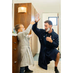 Man wearing UFC DudeRobe in navy color plays with a child in the bathroom, showcasing UFC merch for fight night comfort.