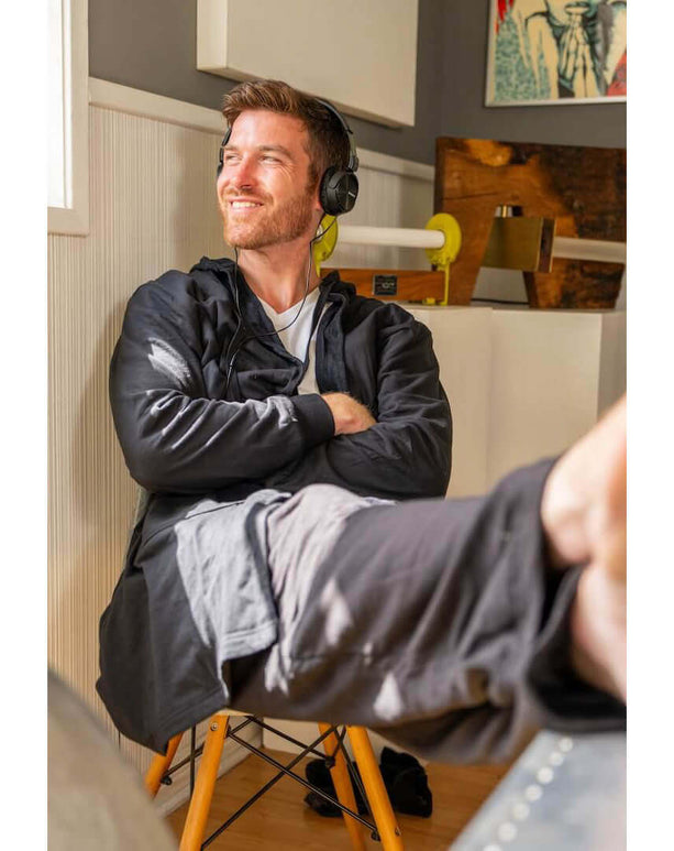 A man enjoying leisure time in a DudeRobe, wearing headphones, showcasing modern luxury in relaxation.