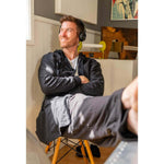 Man relaxing in a black UFC DudeRobe, enjoying music with headphones, showcasing comfortable UFC merch.