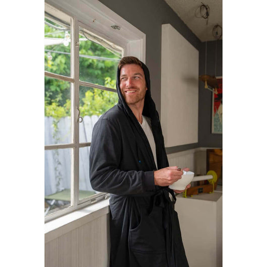 Man enjoying a snack in a black DudeRobe, showcasing UFC merch for ultimate comfort on fight night.