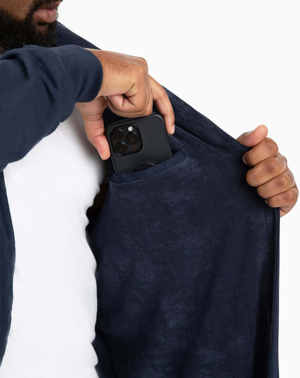 Man using the pocket of a DudeRobe luxury hooded bathrobe to store his phone.