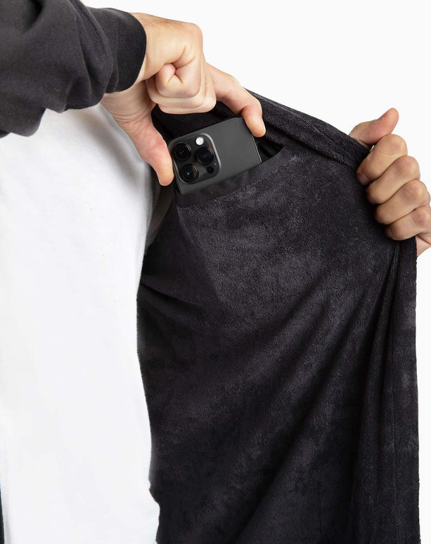 Man using the hidden pocket of The DudeRobe to store a smartphone, showcasing its practical design.