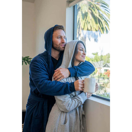 Couple wearing UFC DudeRobe, enjoying a cozy moment by the window, showcasing UFC merch in navy and gray.