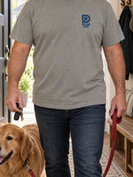 Man at his front door with his dog wearing the DudeRobe Welcome Home tee in Hazy Days