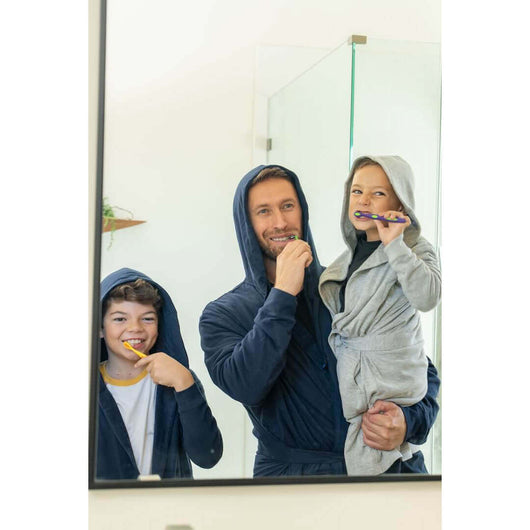 A family wearing The UFC DudeRobe while brushing their teeth in front of a mirror.