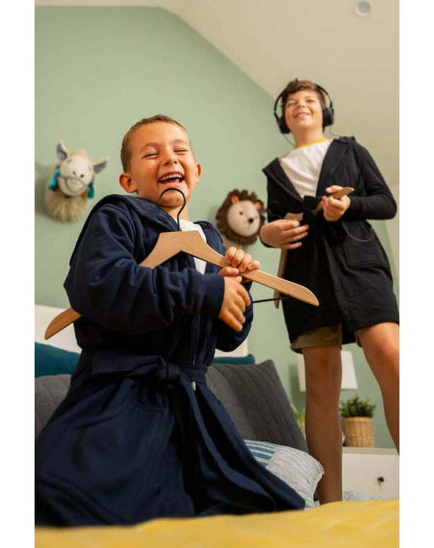 Two kids having fun in stylish hooded bathrobes while relaxing at home, showcasing the luxury kids bathrobe design.