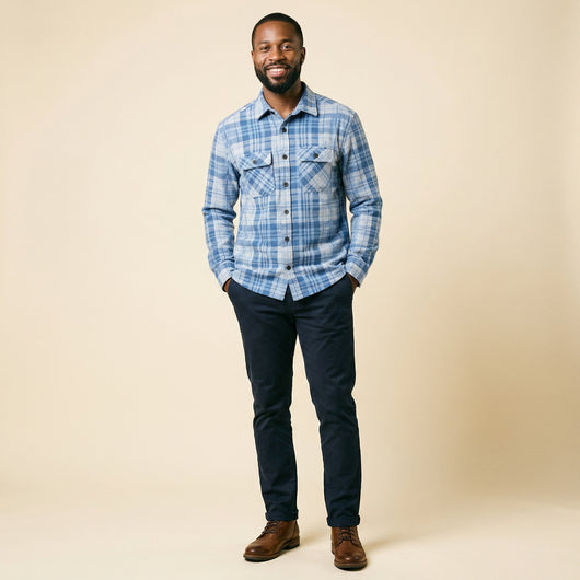 A man wearing The 1-Second Flannel magnetic button shirt, smiling and standing against a beige background.