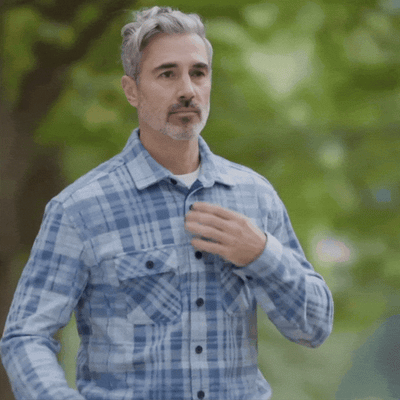 Man wearing The 1-Second Flannel with magnetic button shirt in a green outdoor setting.