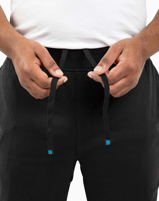 Man adjusting drawstring of DudeShorts, showcasing premium comfort and stylish design for active lifestyles.