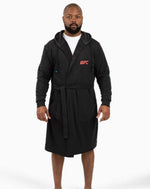 Model wearing a black UFC DudeRobe, showcasing comfortable UFC merch ideal for fans.