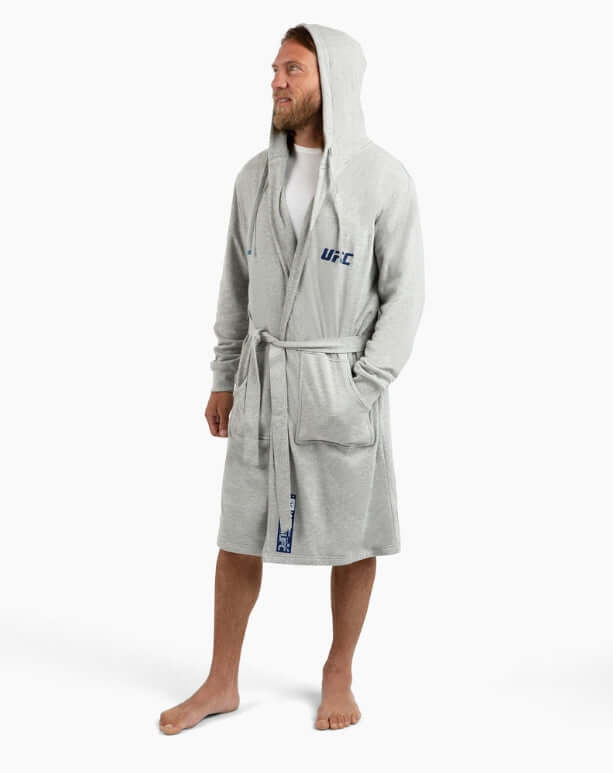 Man wearing a grey UFC DudeRobe with a hood, showcasing modern style and comfort for lounging or post-shower.
