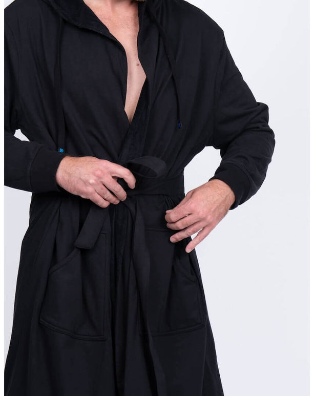 Man adjusting the belt of a sleek black DudeRobe, the ultimate modern robe for style and comfort.