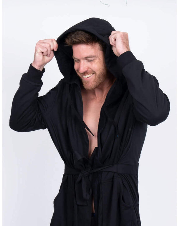 Man smiling in a black DudeRobe with a hood, showcasing modern comfort and style.