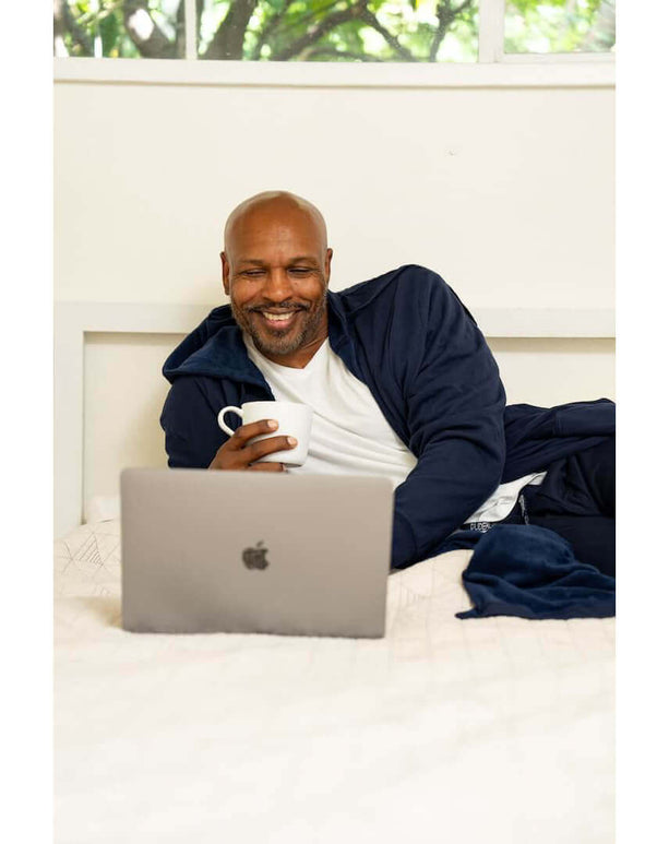 Man in a DudeRobe enjoying coffee while relaxing and using a laptop at home, blending comfort and style.