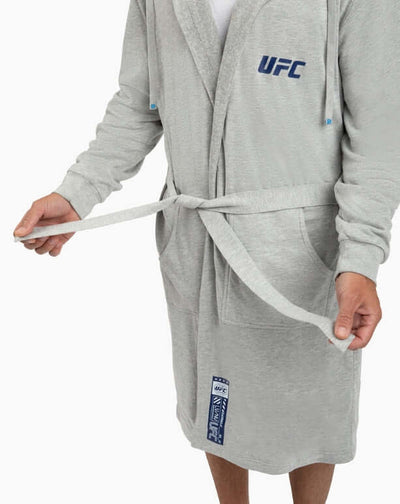 Man tying the belt on the UFC DudeRobe - Grey, a stylish modern bathrobe for lounging and everyday comfort.