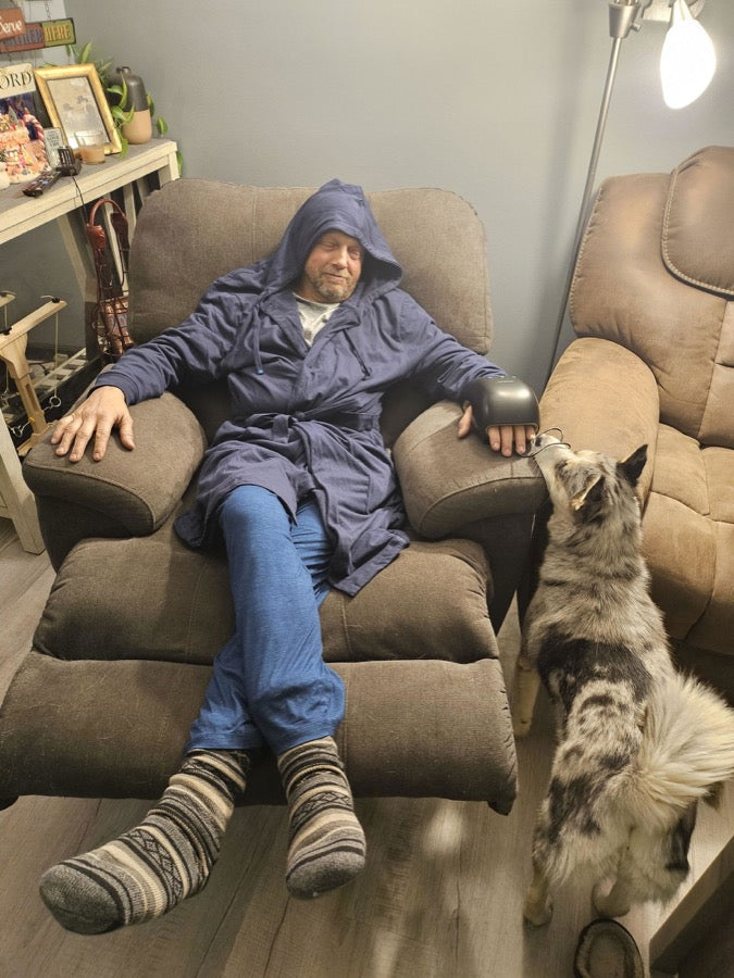 A customer in a navy DudeRobe in his armchair with his dog