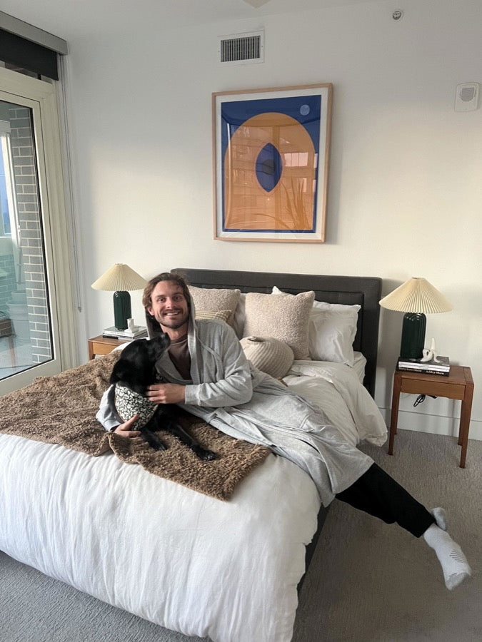 A customer relaxing in a grey DudeRobe with his dog