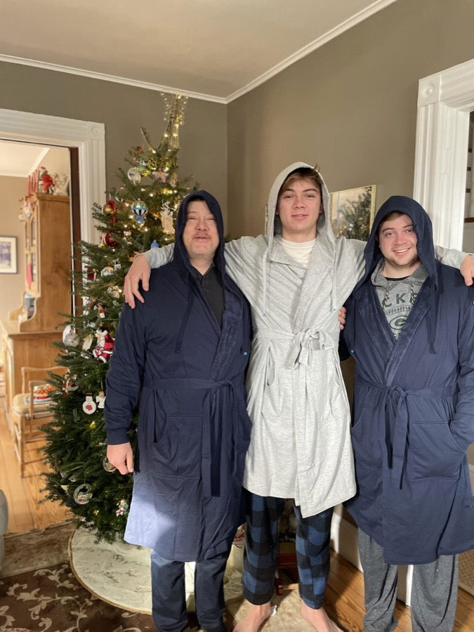 A dad and two sons in DudeRobes beside the Christmas tree