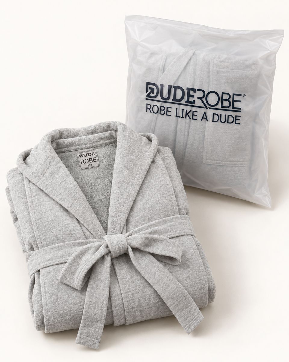 A folded grey DudeRobe beside its DudeRobe bag