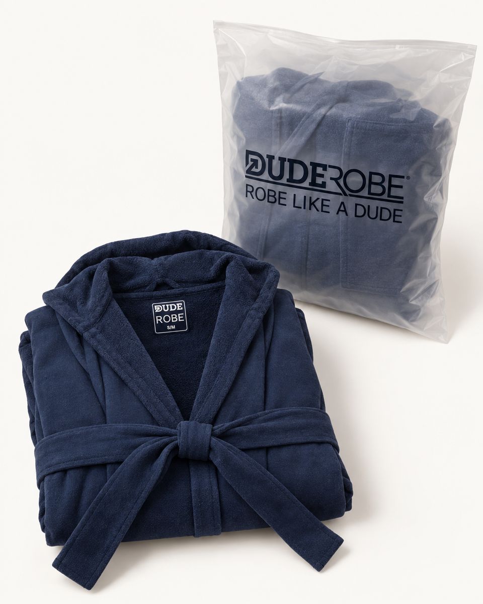 A folded navy DudeRobe beside its DudeRobe bag